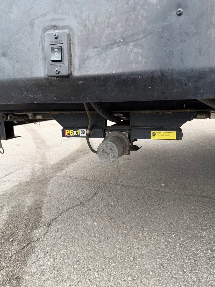 Black RV sewer outlet with electrical switch on exterior.