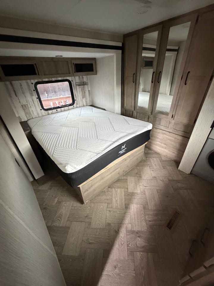 Bedroom in a camper with a bed, closets, and a window.