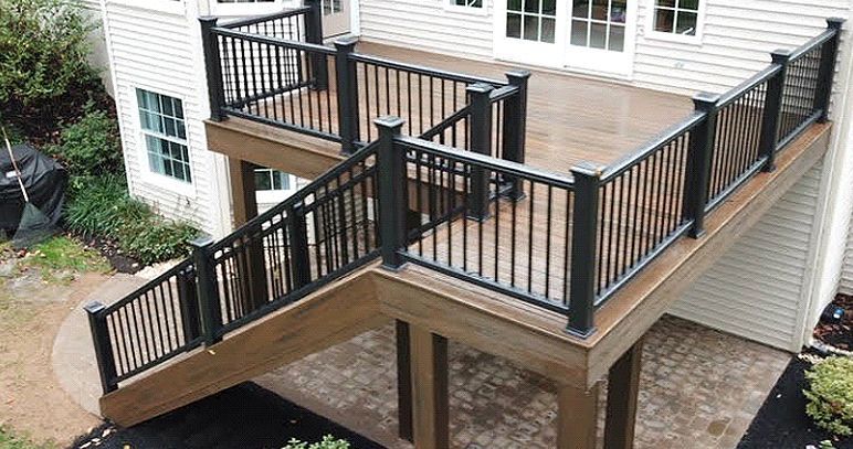 An aerial view of a wooden deck with a black railing and stairs leading up to it.