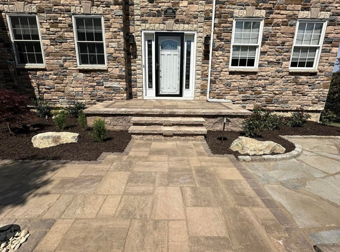 A stone house with a brick walkway leading to the front door.