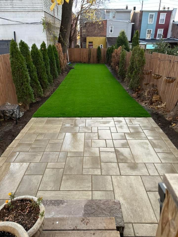 A backyard with a patio and a lush green lawn.