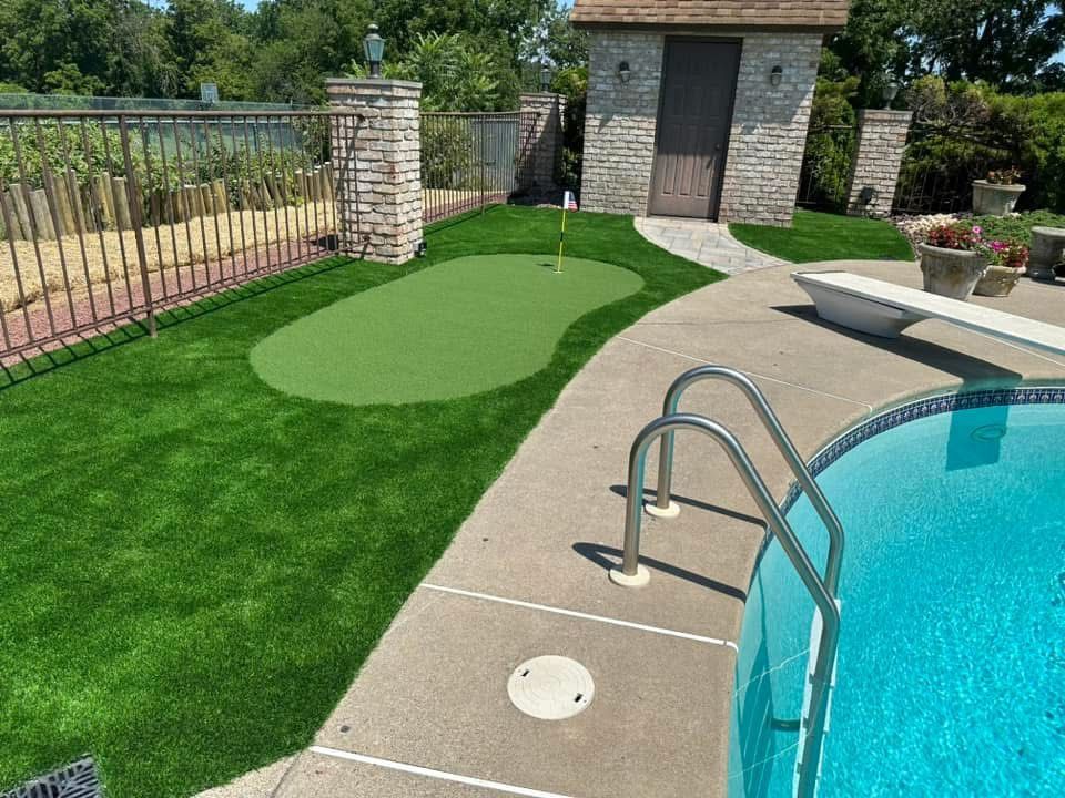 A swimming pool with a putting green in the backyard.