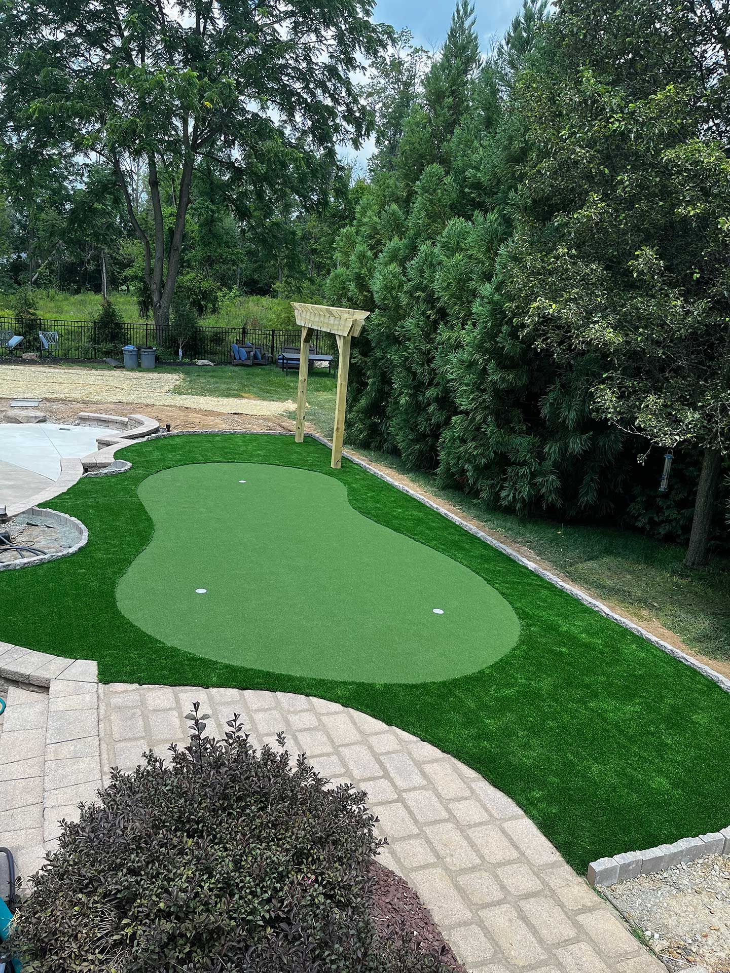 There is a putting green and artificial  grass in the middle of the backyard