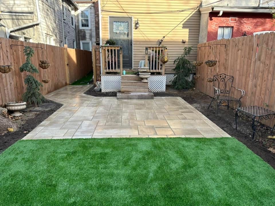 A backyard with a patio, chairs, and a wooden fence.