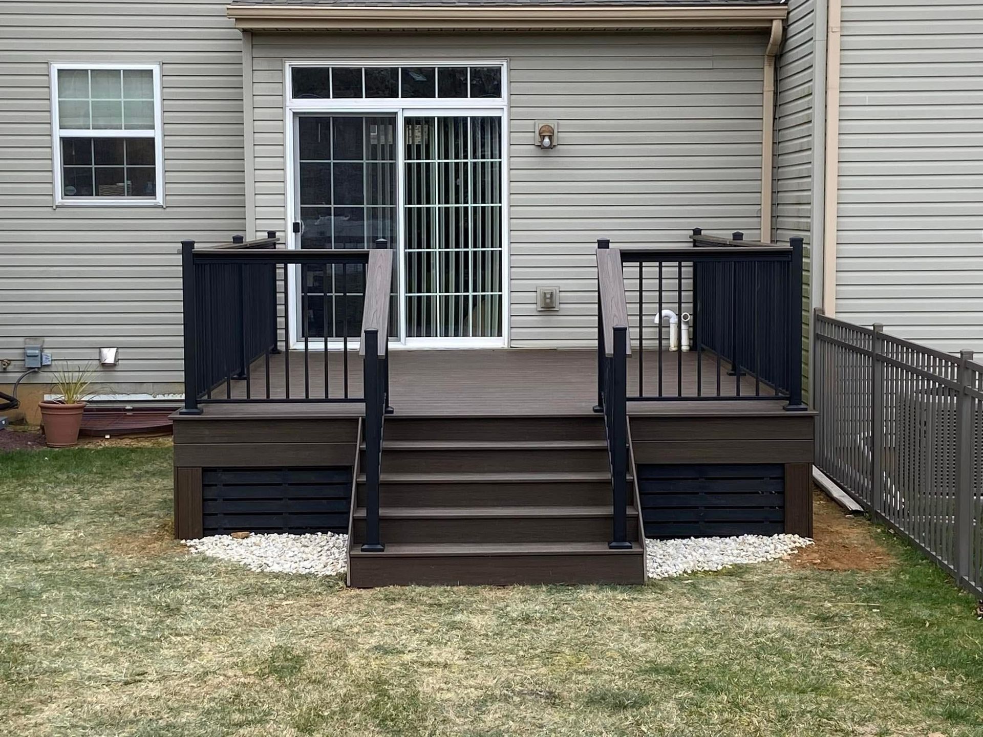 A deck with stairs leading up to it is in the backyard of a house.