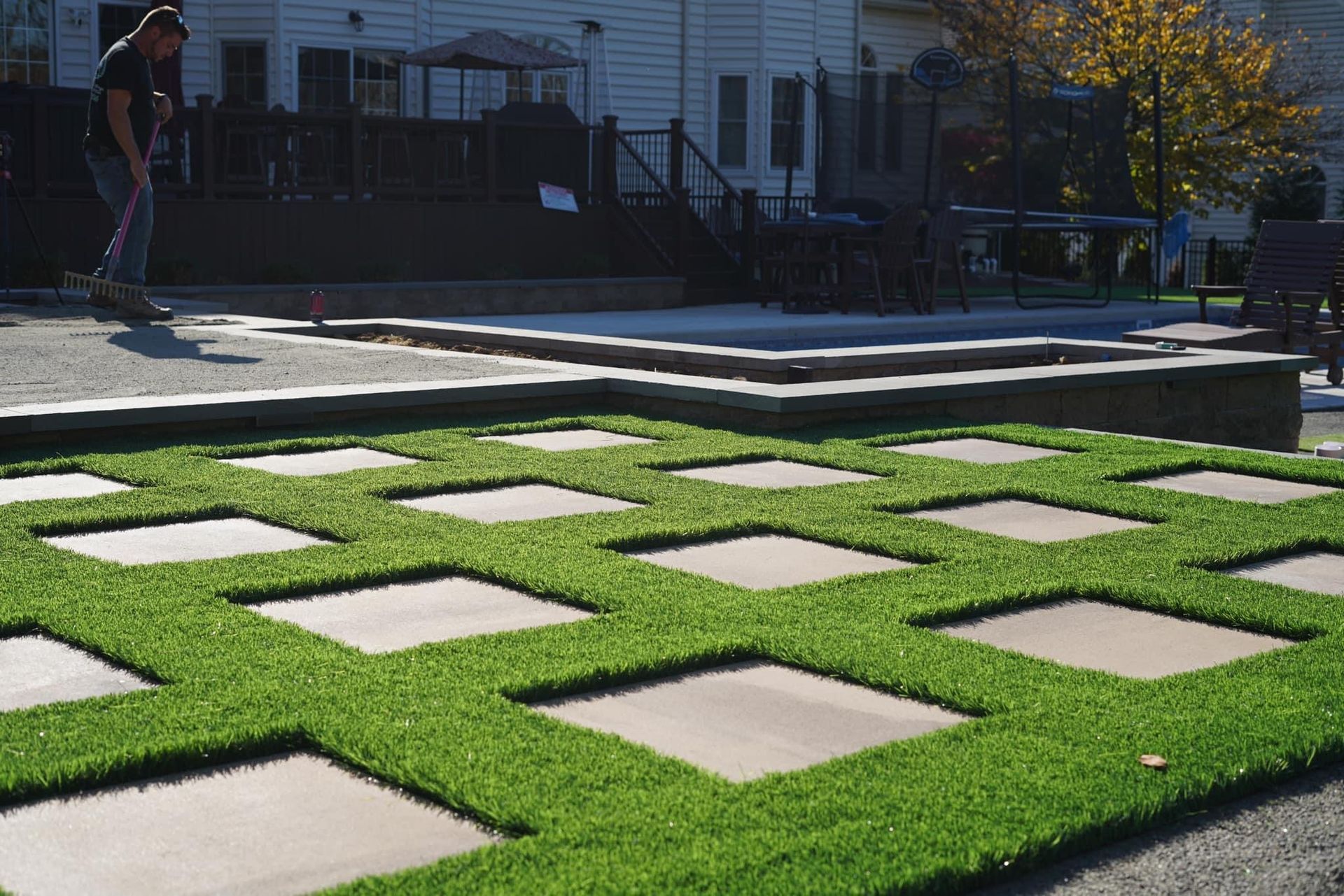 patterened grass with a person holding a rake in the background