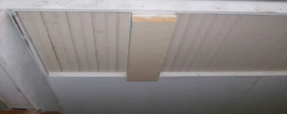 Wooden ceiling with a rectangular wood beam attached.