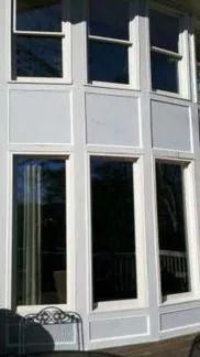 Exterior view of a building with white-framed windows and light gray panels.