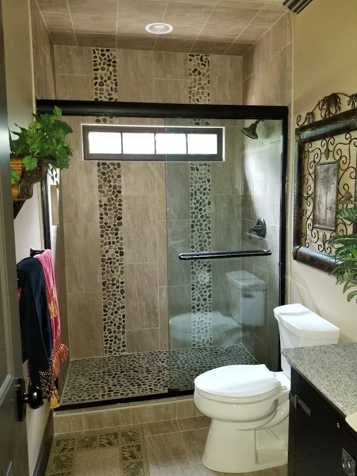 Bathroom with a glass shower, toilet, and decorative tile.