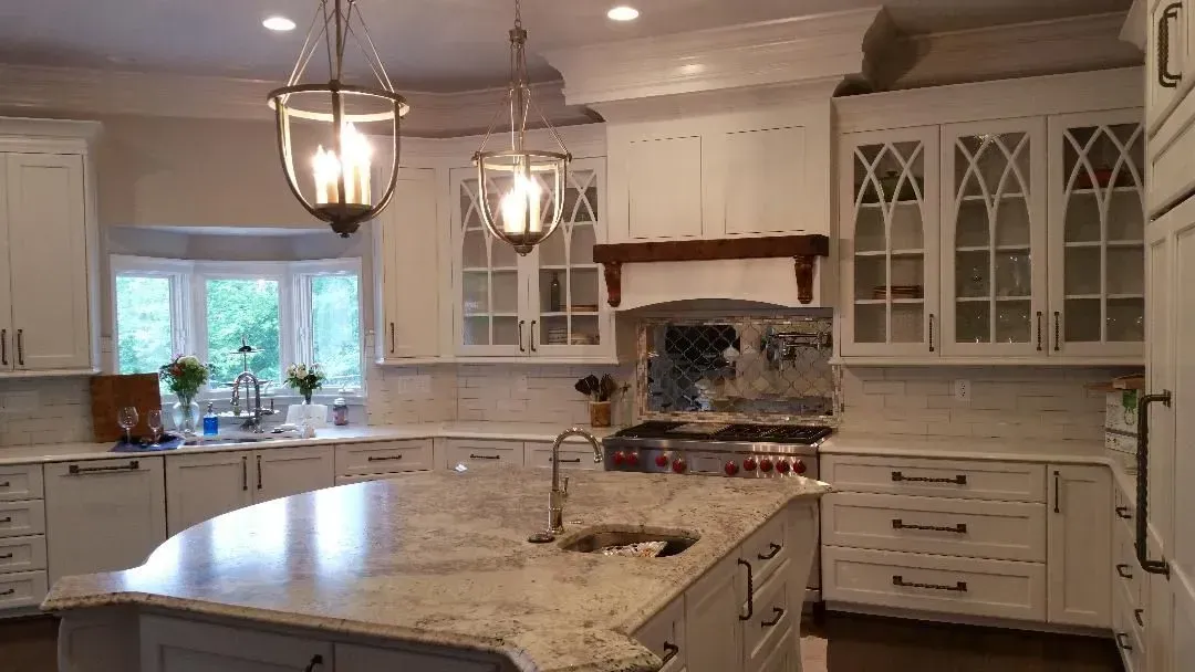 White kitchen with island, pendant lights, and bay window.