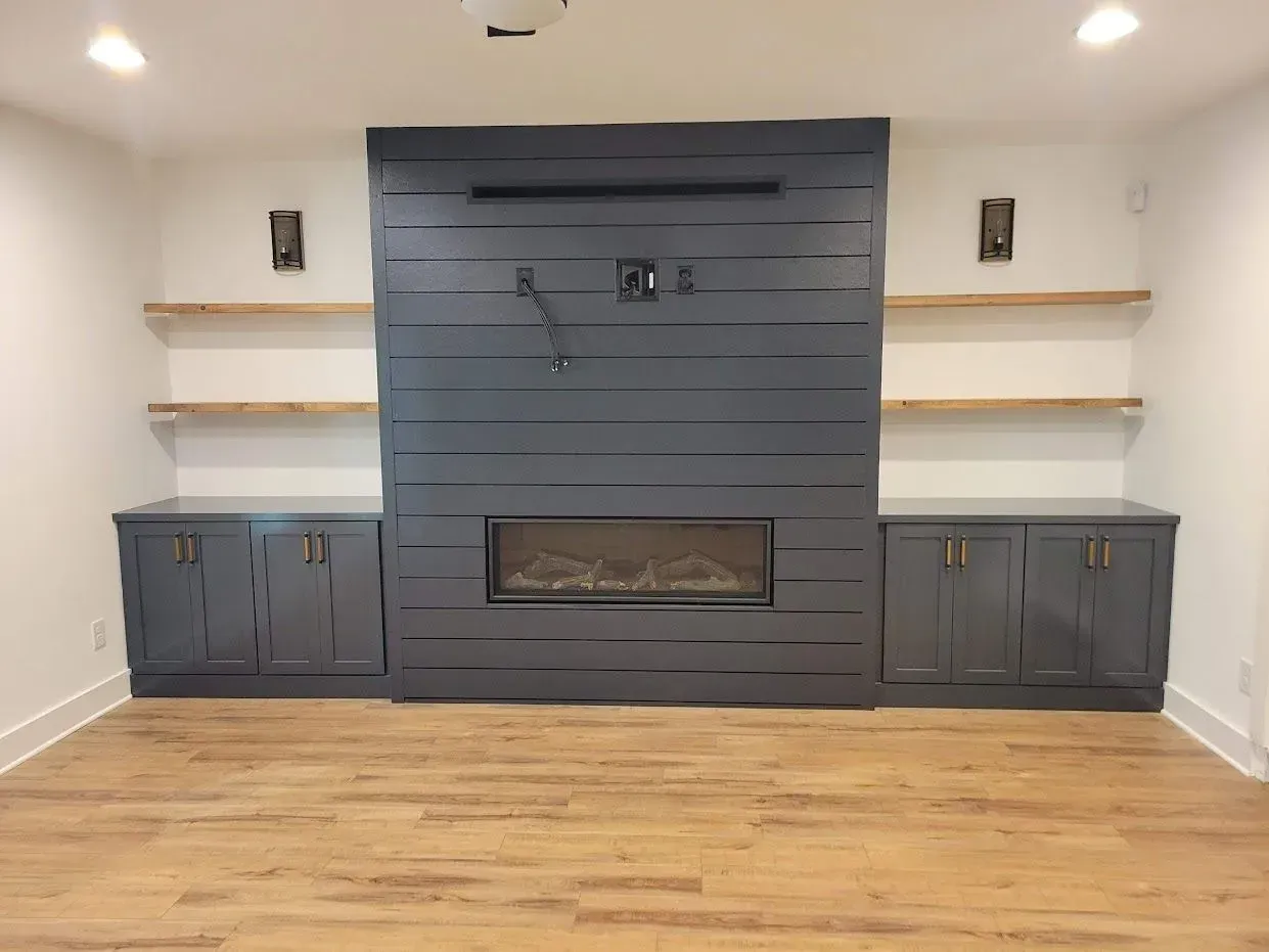 Living room with gray fireplace, built-in cabinets, shelves, and hardwood floor.