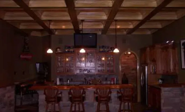 Bar area with wooden beams, bar stools, and a television above the bar.