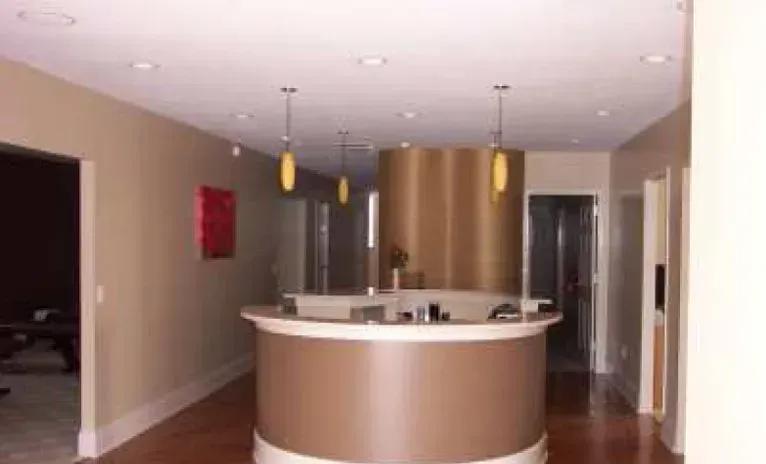 Reception area with brown curved desk, pendant lights, and beige walls.