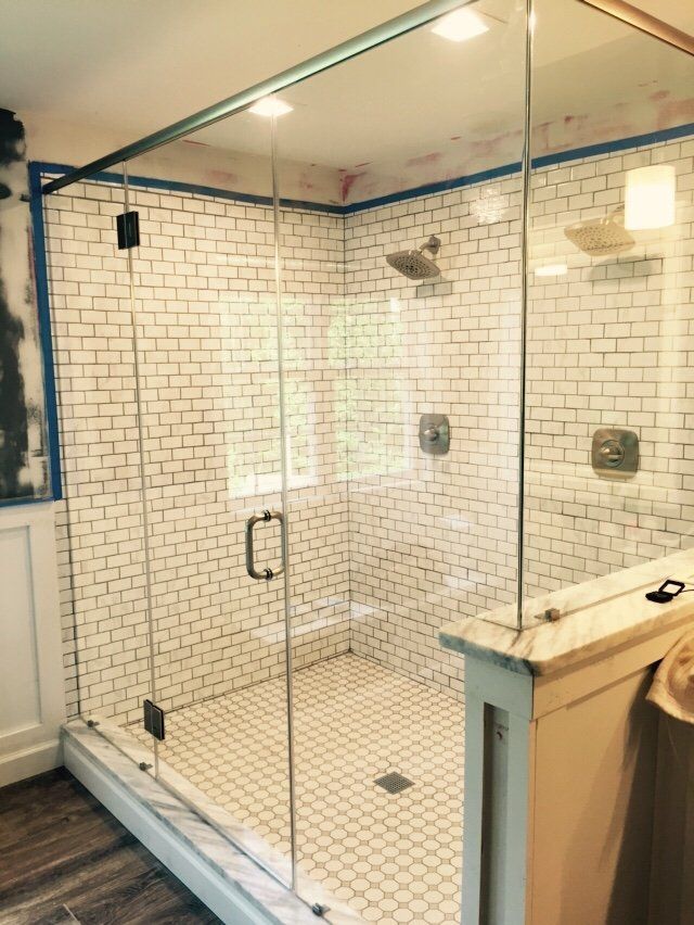 Glass-enclosed shower with white subway tile walls and small, white tile floor.