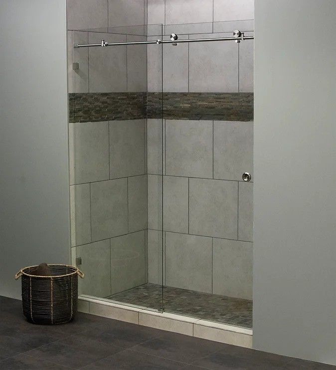 Glass shower with sliding door, gray tile, decorative stone accent, and dark floor.