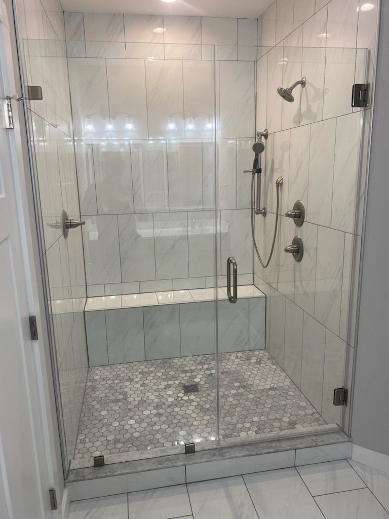 Glass shower with white tiled walls and pebble floor.
