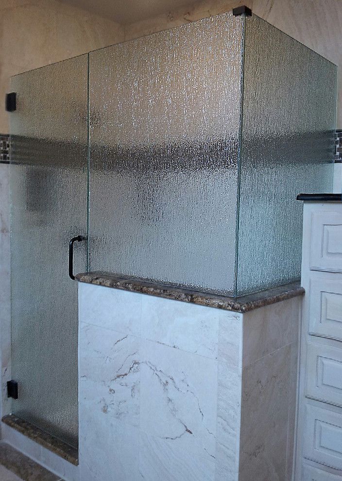 Glass shower enclosure with textured glass panels, black hardware, and marble surround.
