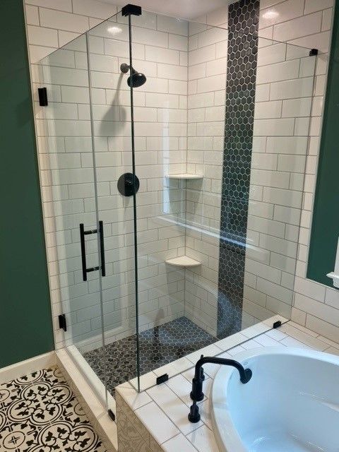 Modern bathroom with glass shower, black fixtures, white subway tiles, dark mosaic accent, and tub.