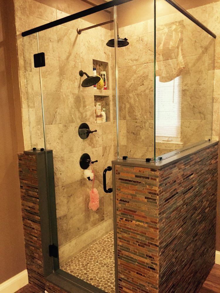 Shower stall with stone tile accents, glass door and panels, black hardware.