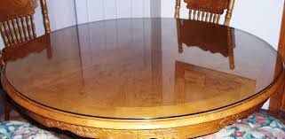 Round wooden table with a glossy surface, reflecting chairs and a room.
