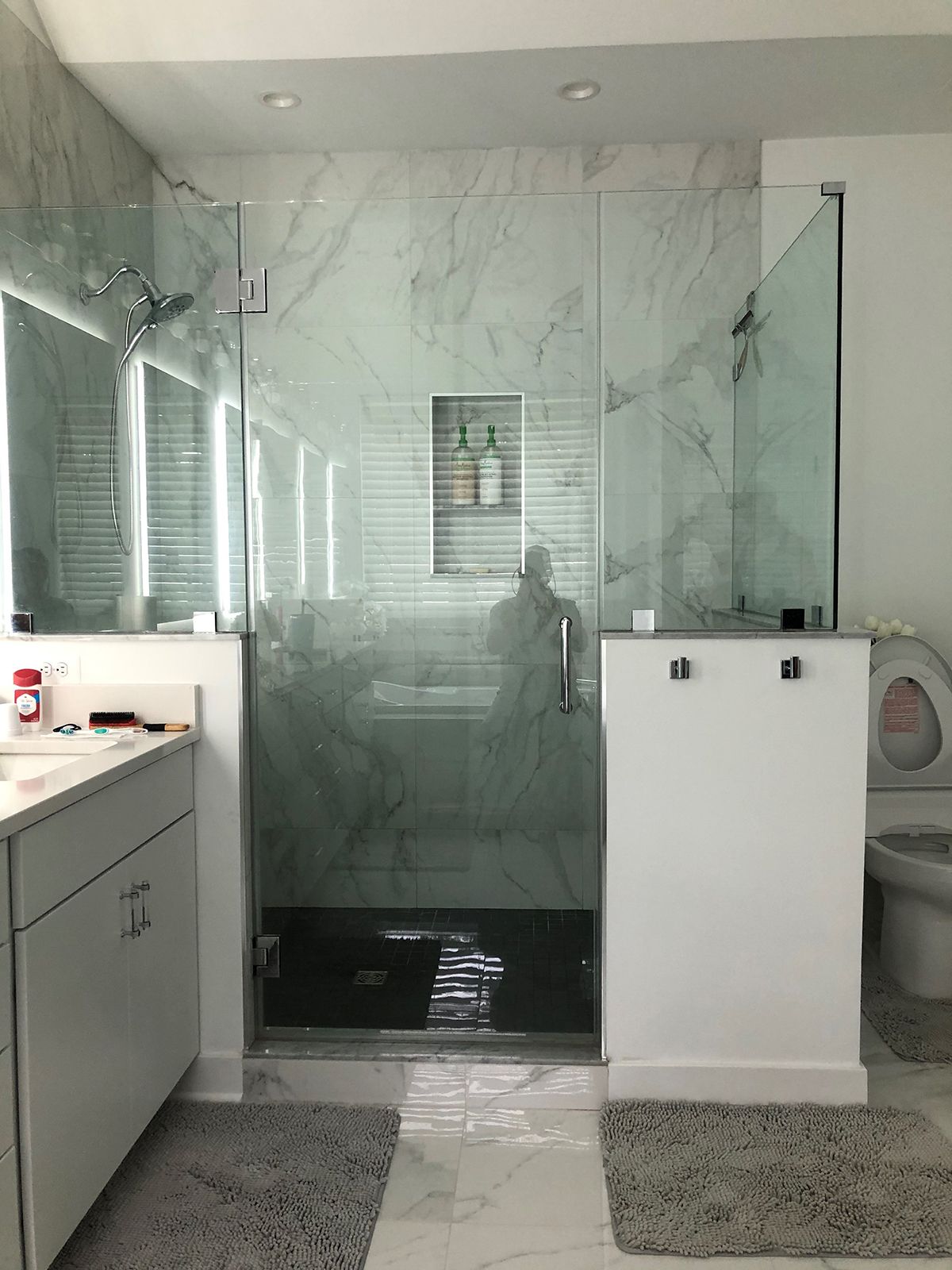 Modern bathroom featuring a glass-enclosed shower with marble-look tile, a vanity, and a toilet.