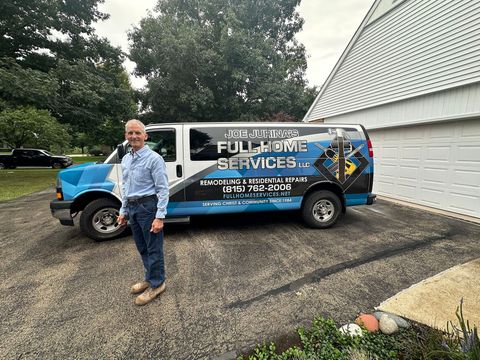 Man standing beside a blue service van in a driveway, with a house and trees in the background