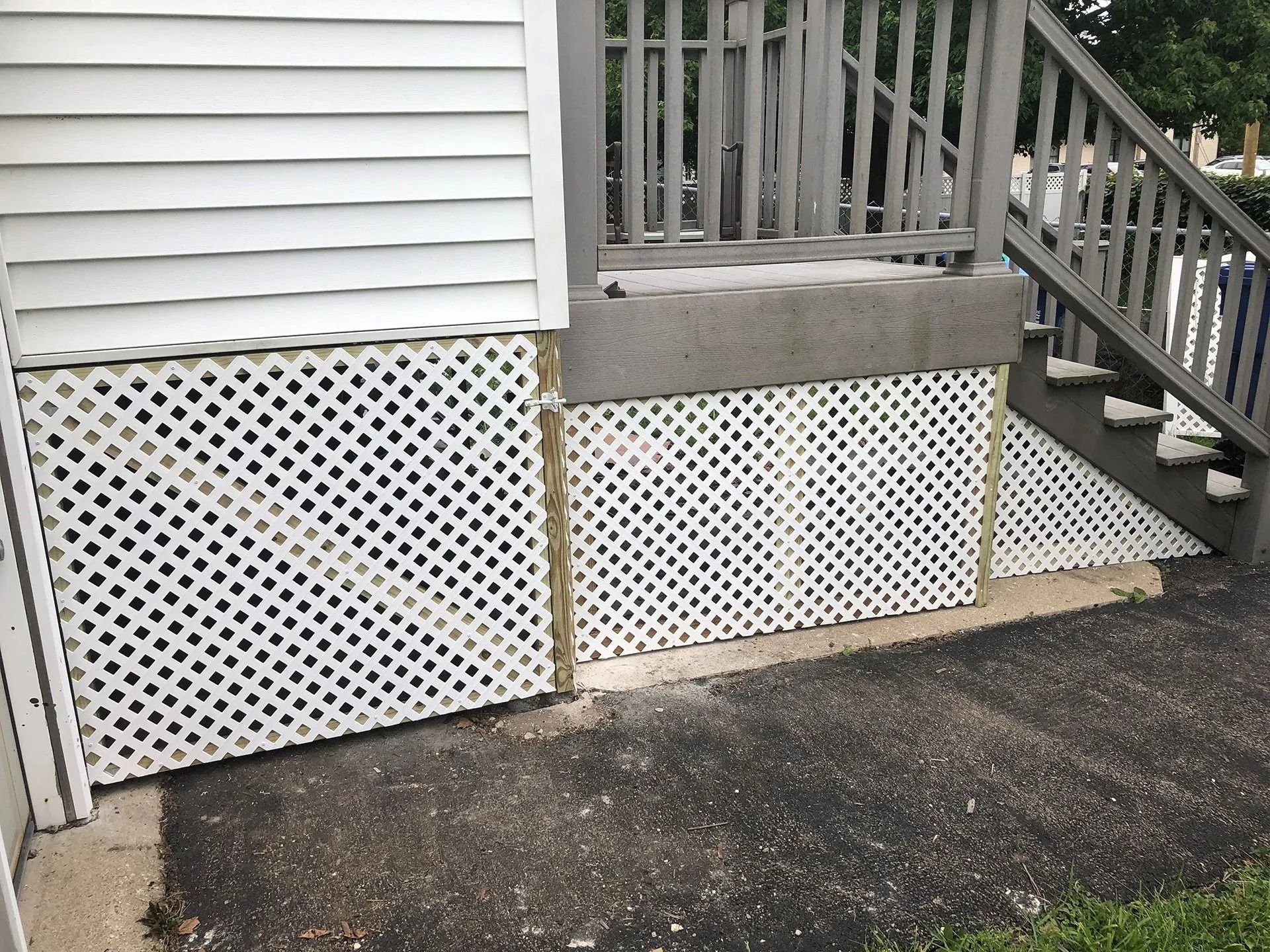 White lattice skirting under a house porch beside concrete steps and a gray railing