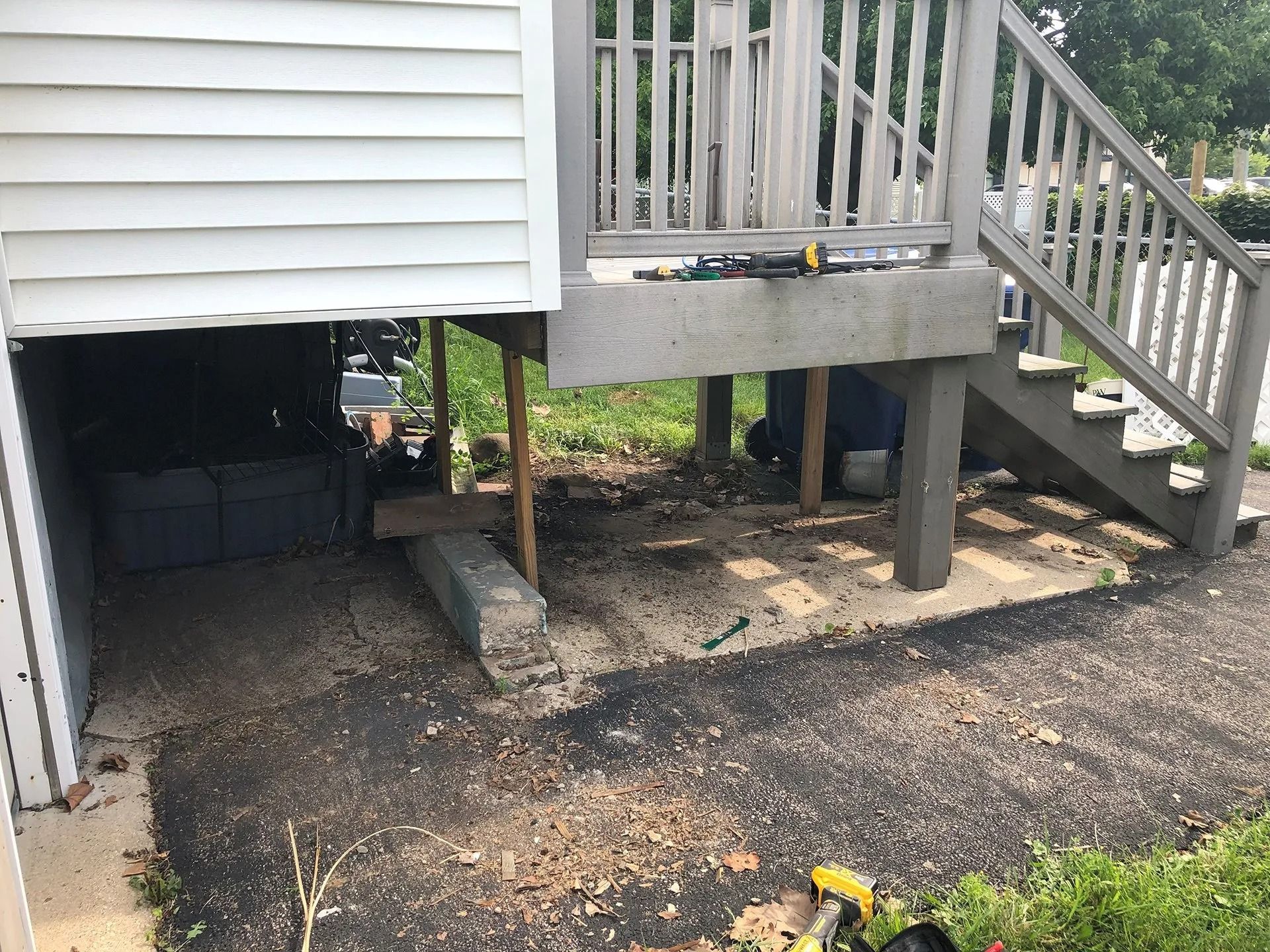Under-deck storage area with gravel ground, stairs, and a raised wooden porch.
