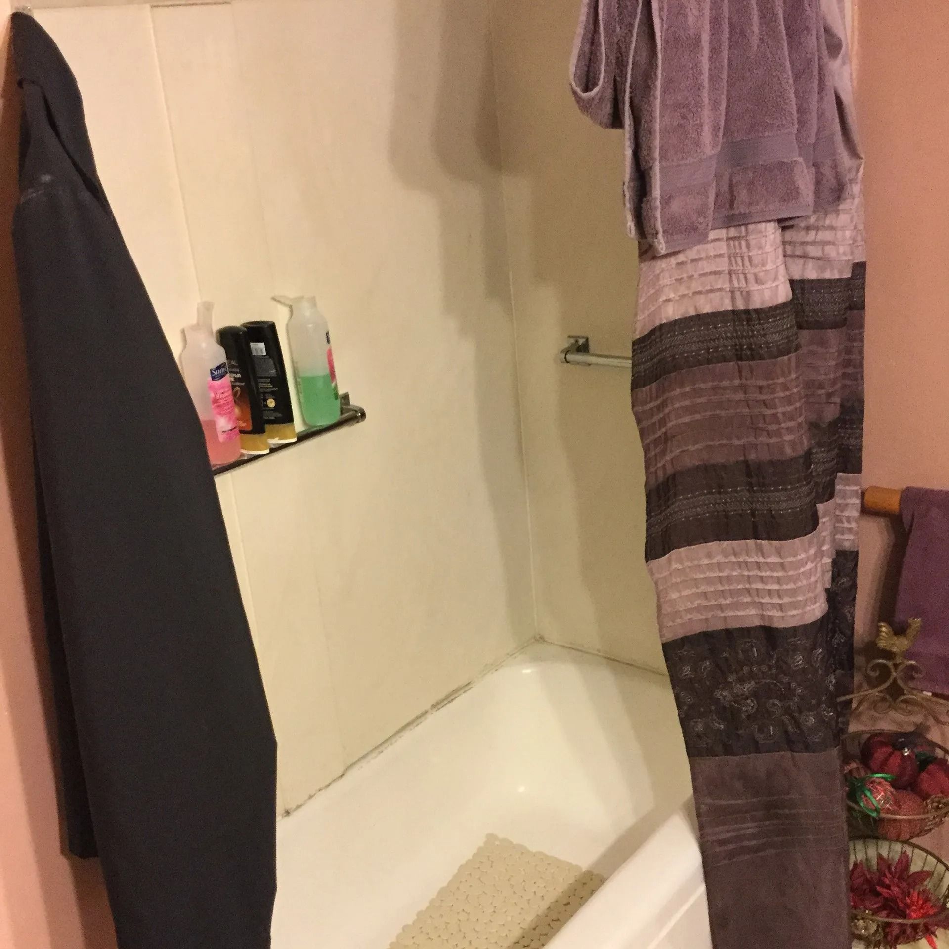 Small bathroom with a bathtub, hanging towels, and toiletries on a corner shelf.