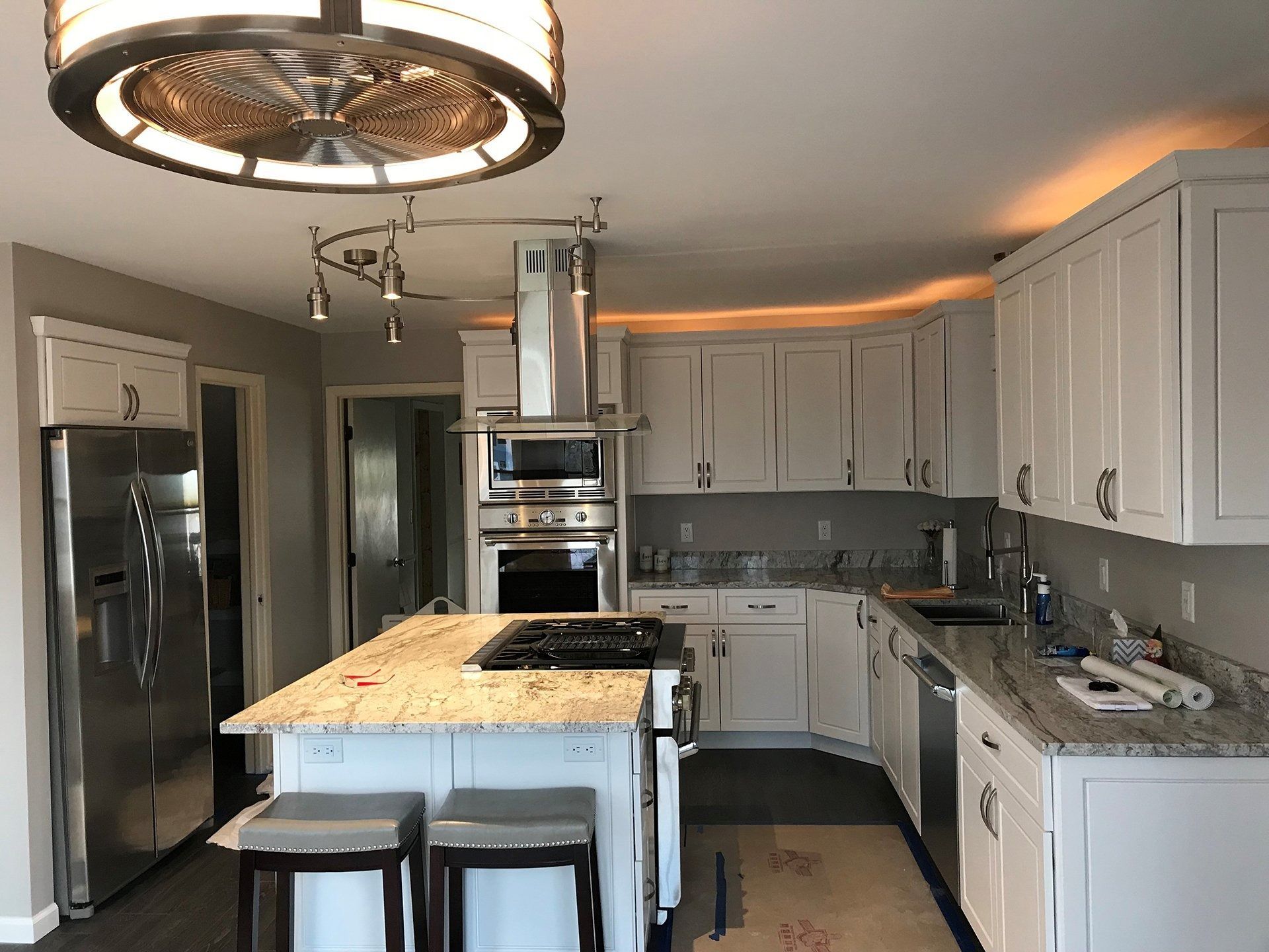 Bright modern kitchen with white cabinets, stainless appliances, island, and two stools
