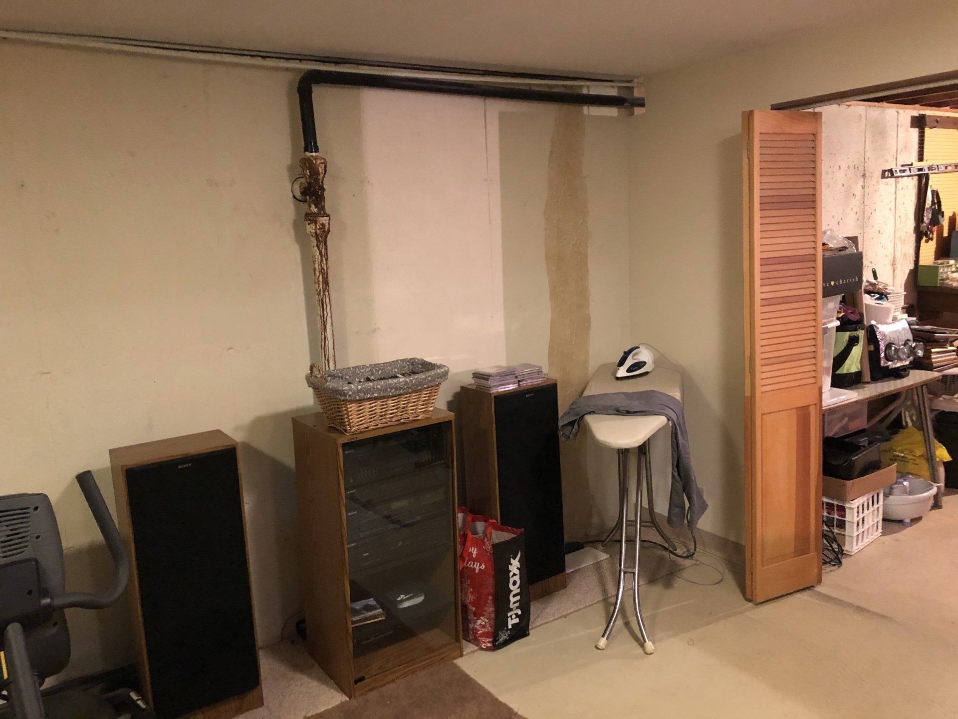 Basement room with shelves, a small table, and an open wooden closet door.