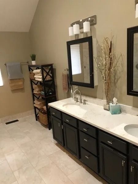 Modern bathroom with dark vanity, white countertop, mirror, shelving, and beige tile floor