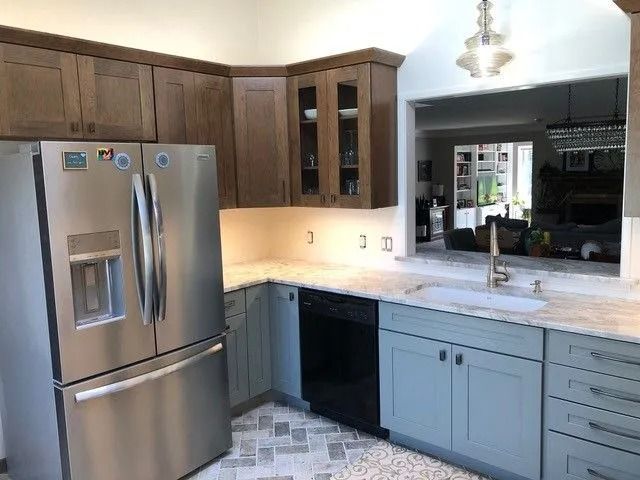 Modern kitchen with stainless steel fridge, light blue cabinets, and marble countertop