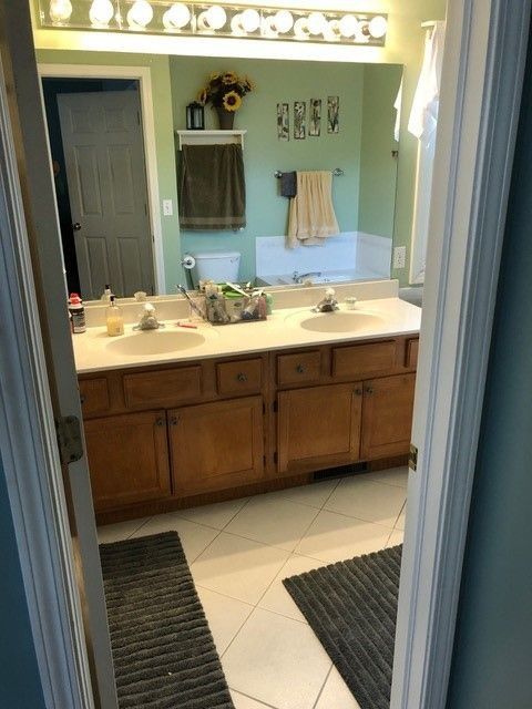 Bathroom with double vanity, mirrors, lights, and towels on a mint green wall