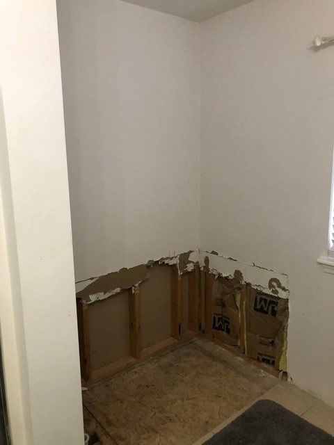 Empty corner of a room with exposed drywall and cardboard covering the lower walls during renovation