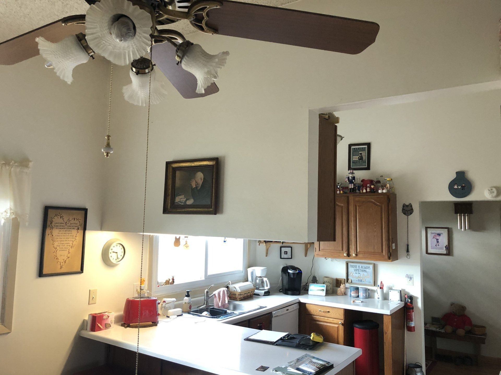 Kitchen with white cabinets, ceiling fan, sink, and a pass-through to a living room