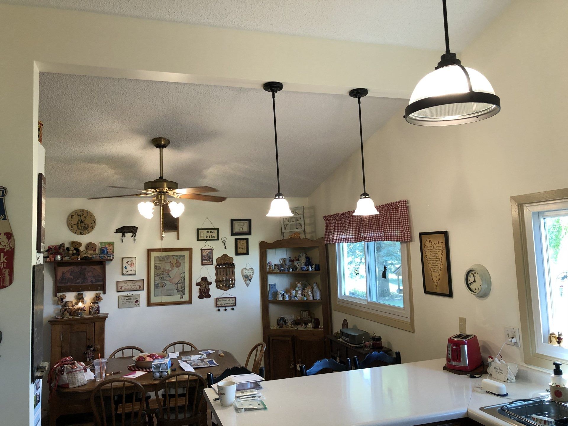 Cozy dining room with ceiling fans, hanging lights, wall art, and a window over the sink