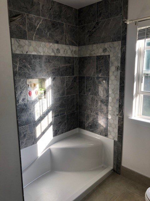 Modern tiled walk-in shower with a built-in white bench and window light.