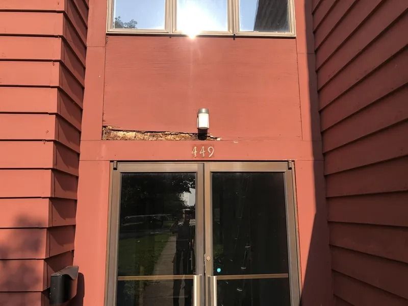 Red apartment building entrance with glass doors and the number 145 above them