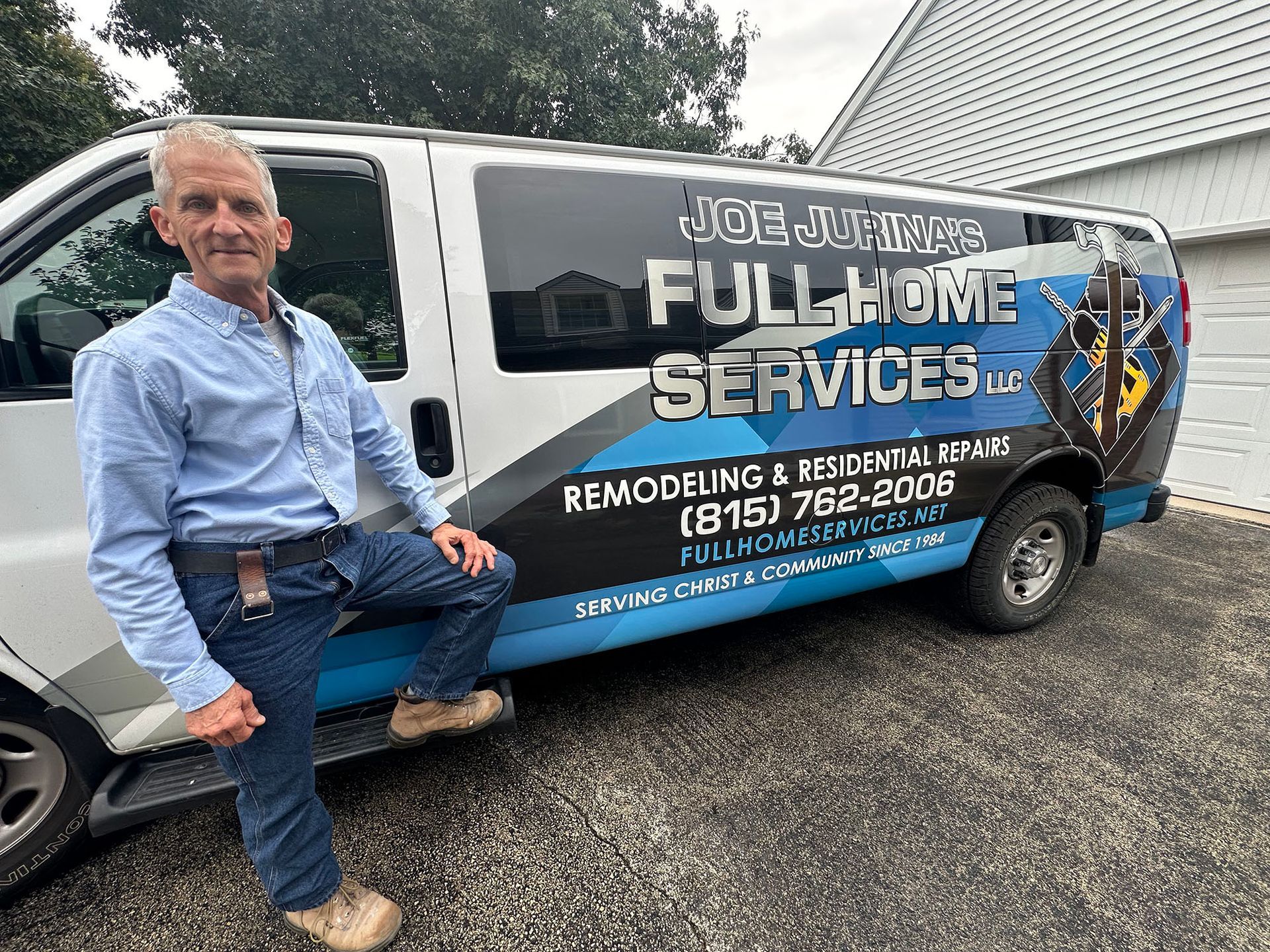 Man sitting beside a white service van with “Joe’s Full Home Services” signage in a gravel lot
