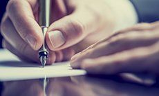 Learn More About Wills & Estate Planning Man writing on a document