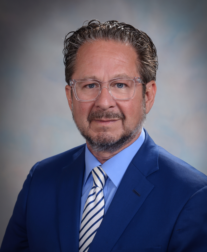 A man in a blue suit and tie is smiling for the camera.