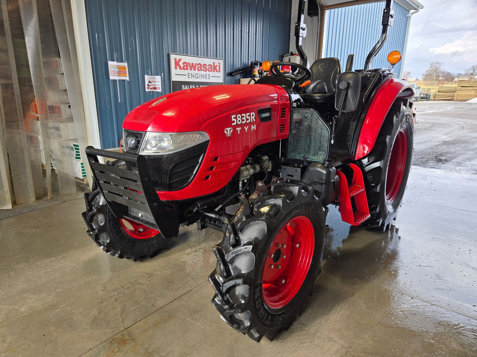 A red and black lawn mower is parked in a gravel lot.