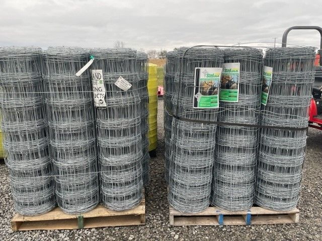 A bunch of rolls of wire fencing are stacked on top of each other on a wooden pallet.