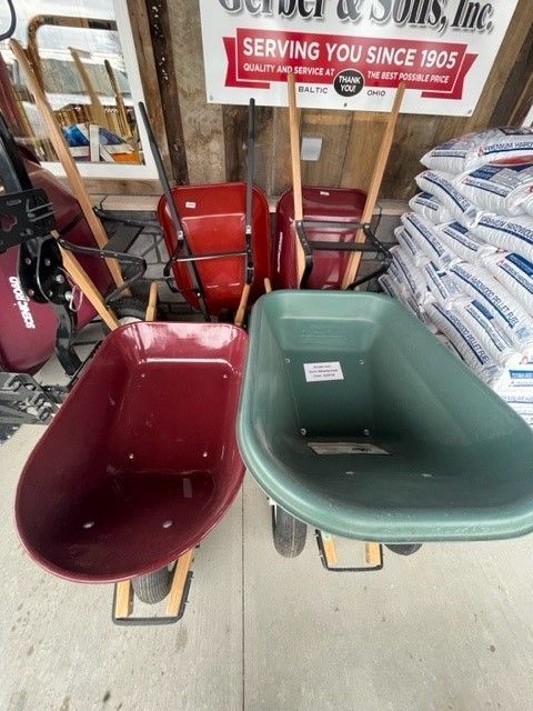 Several wheelbarrows are lined up in front of a sign that says serving you since 1905.
