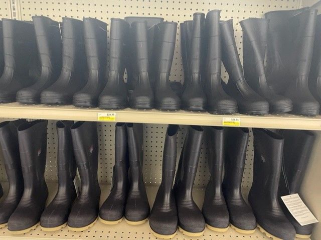 A row of black rain boots are lined up on a shelf.