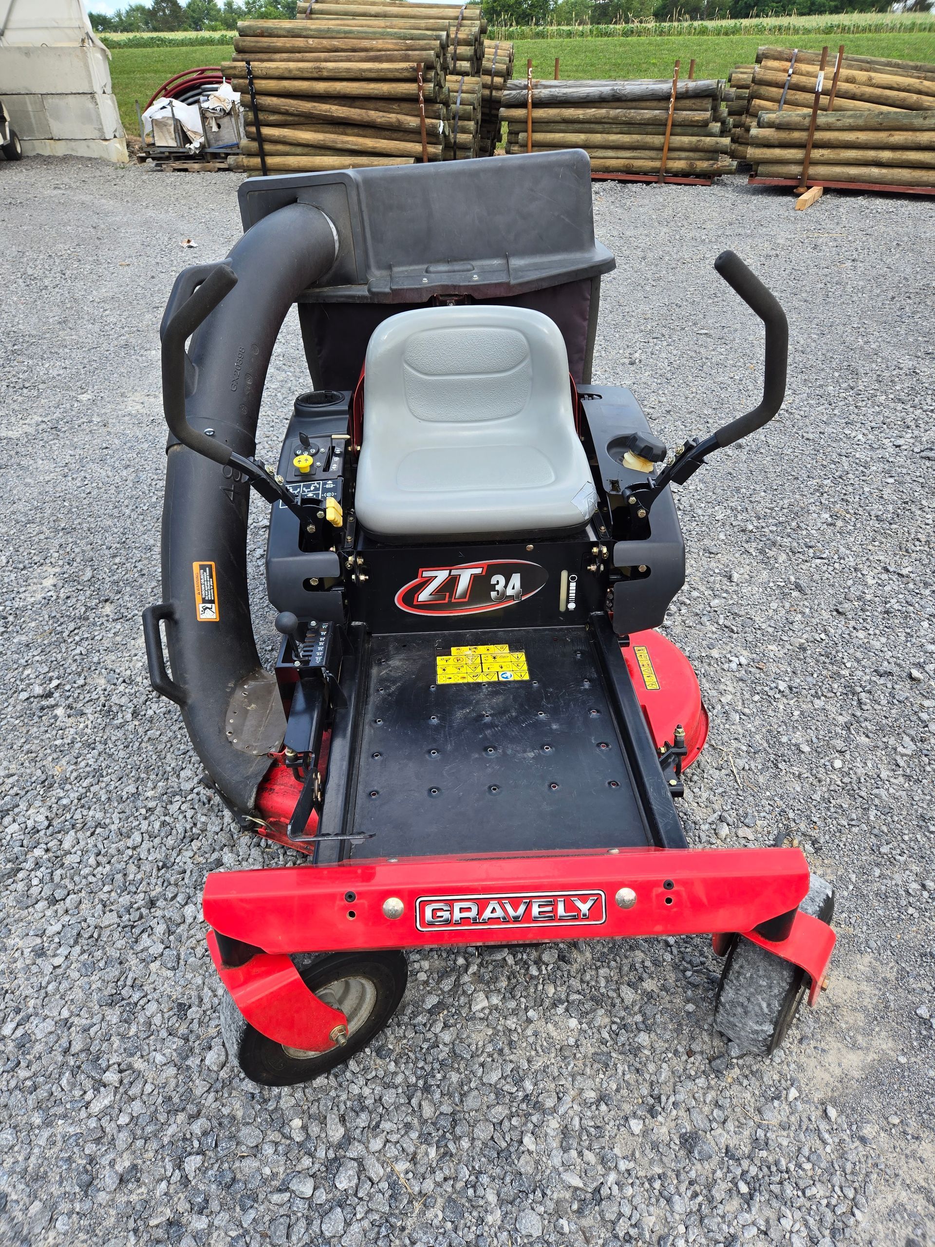 A red and black lawn mower is parked in a gravel lot.
