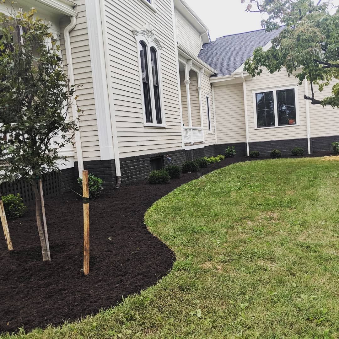 White house exterior with fresh dark mulch beds and a green lawn, seen from the side yard