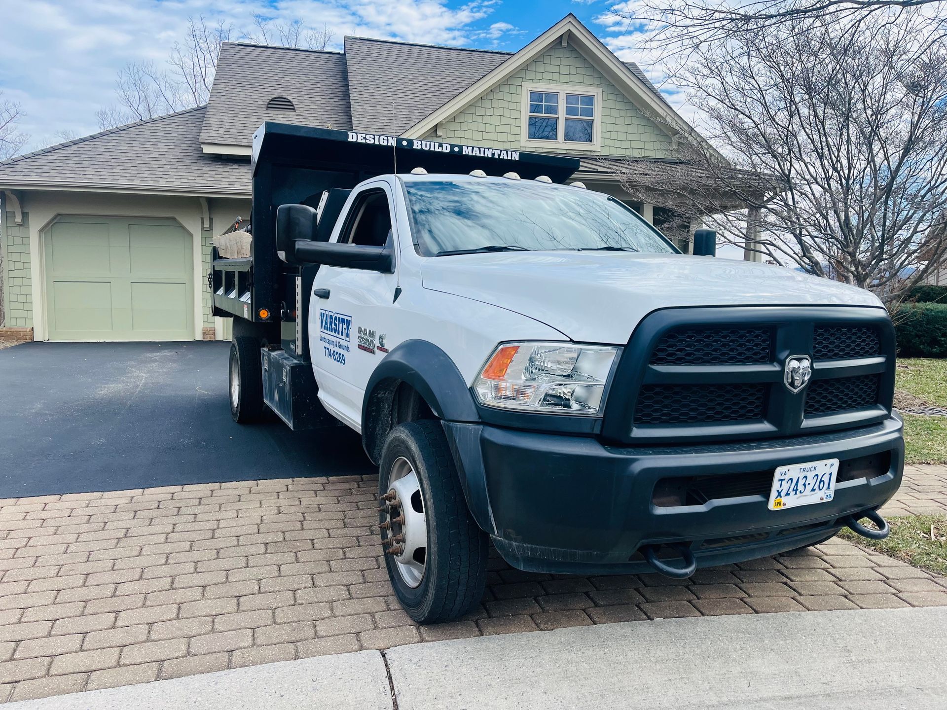 White dump truck parked in a driveway in front of a suburban house