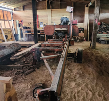 A sawmill is sitting inside of a wooden building.